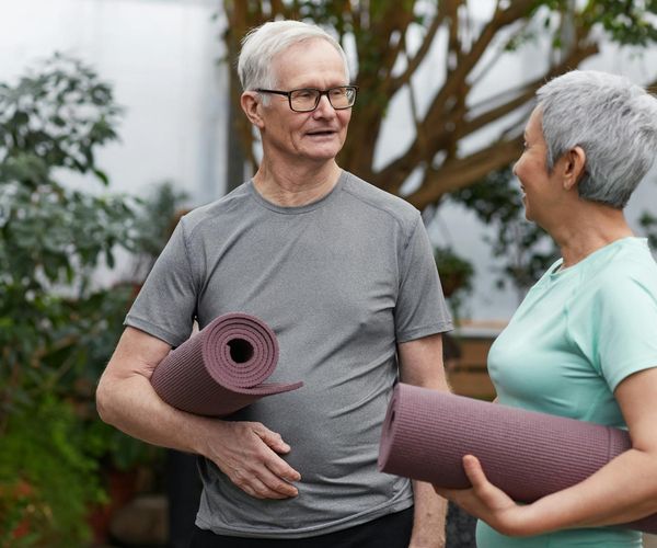 Diverse group of women smiling and holding yoga mats.
